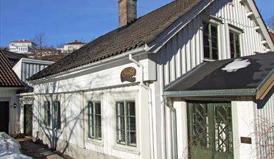 a white old wooden house with green doors and windows